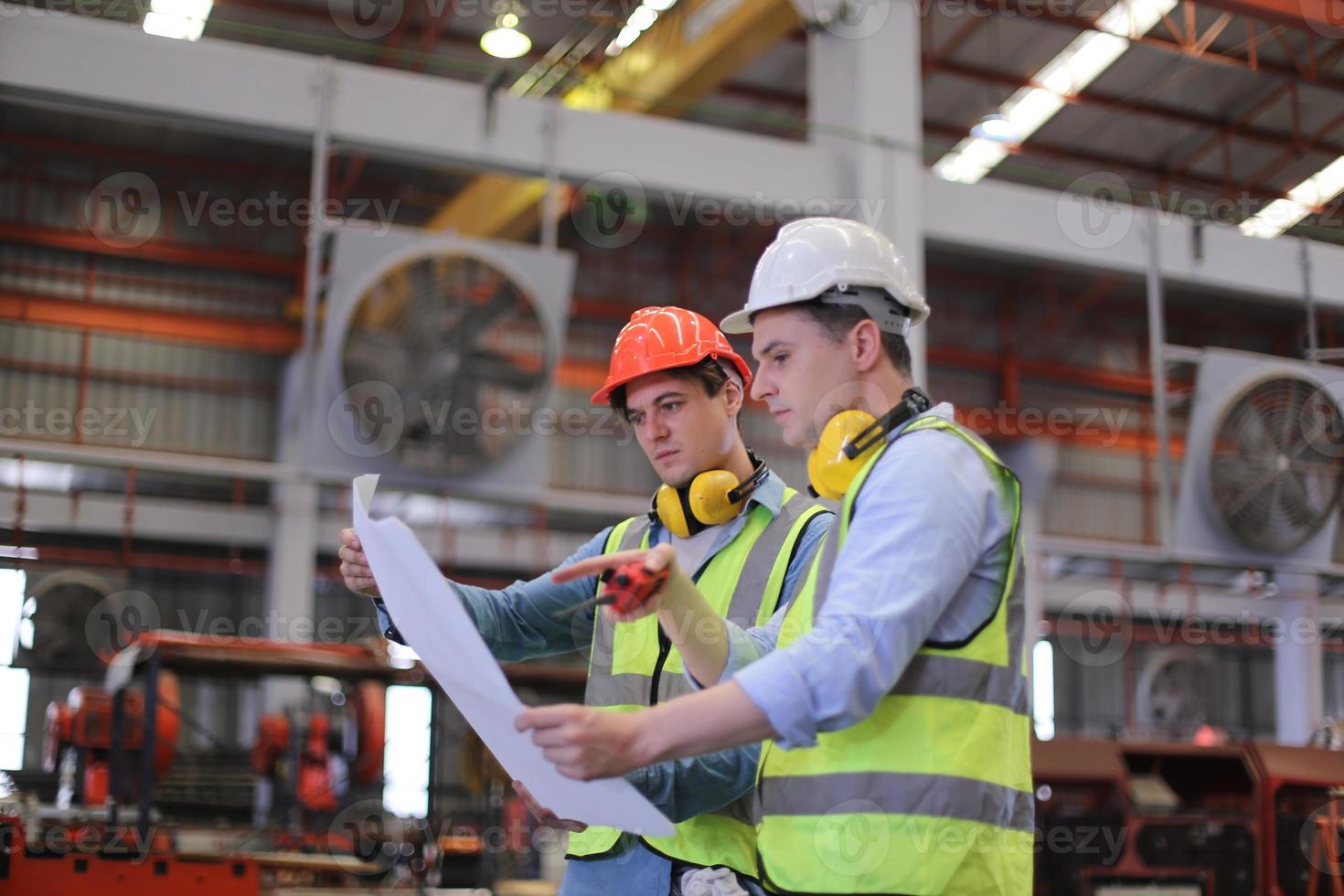 mannen industrieel ingenieur die een veiligheidshelm draagt terwijl hij in een zware industriële fabriek staat. het onderhoud van het werken aan industriële machines en het controleren van de installatie van het beveiligingssysteem in de fabriek. foto