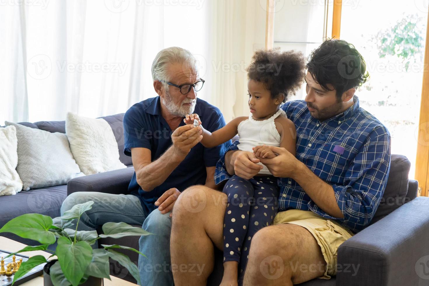 diverse vriendelijke familie zit op de comfortabele bank in een gezellige woonkamer, een multiraciale ouders en hun kinderen genieten van tijd samen thuis foto