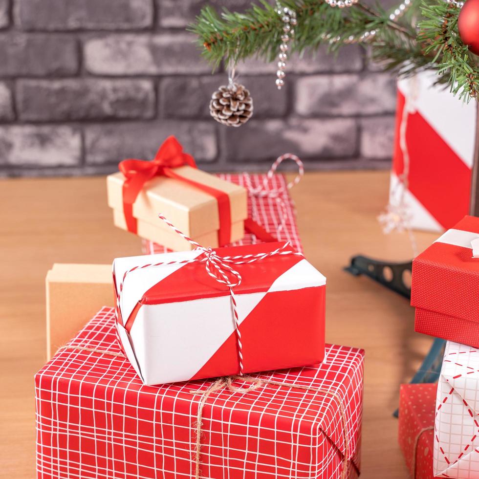 versierde kerstboom met ingepakte mooie rode en witte geschenken thuis met zwarte bakstenen muur, feestelijk ontwerpconcept, close-up. foto