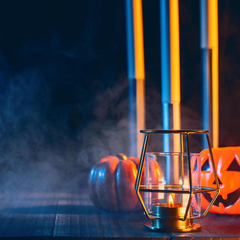 Halloween-vakantieconceptontwerp van pompoen, kaars, spookachtige decoraties met blauwe toonrook rond op een donkere houten tafel, close-up shot. foto
