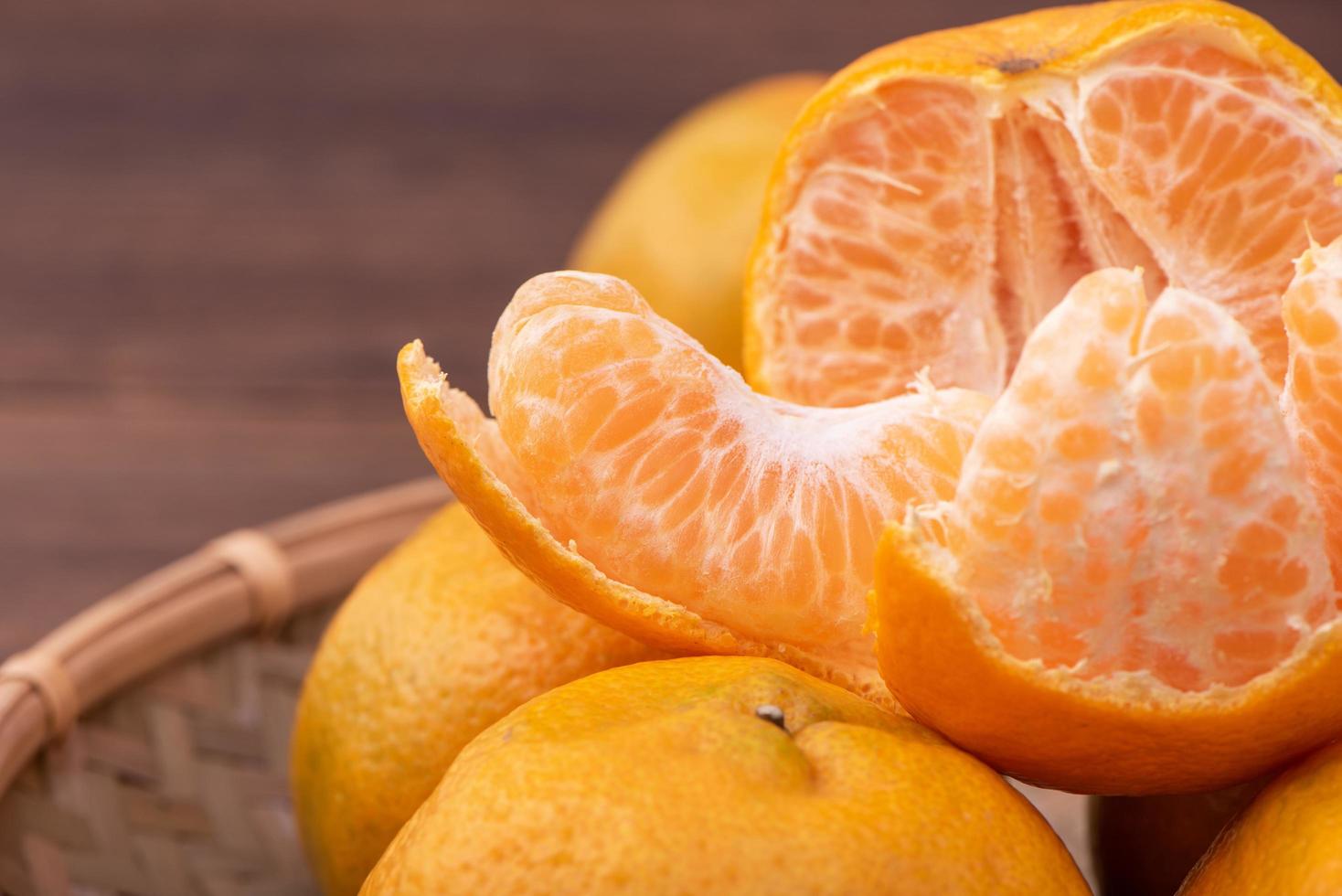 frisse, mooie oranje kleur mandarijn op bamboe zeef over donkere houten tafel. seizoensgebonden, traditioneel fruit van chinees nieuw maanjaar, close-up. foto