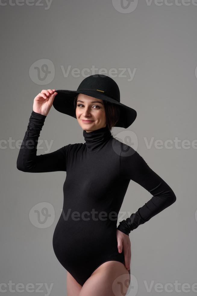 jonge mooie zwangere vrouw in zwarte Romper en hoed. foto