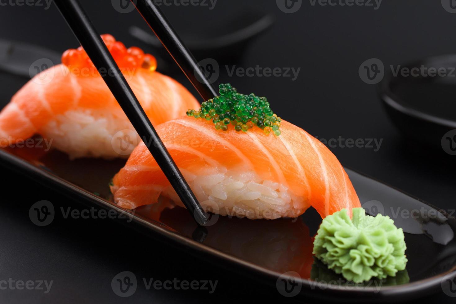 zalm sushi nigiri in stokjes op zwarte achtergrond foto