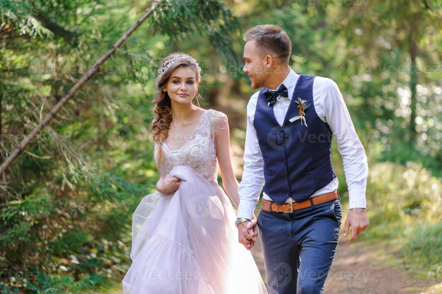 een aantrekkelijk pasgetrouwd stel, een gelukkig en vreugdevol moment. een man en een vrouw scheren en kussen in vakantiekleren. bohemien-stijl bruiloft cermonia in het bos in de frisse lucht. foto