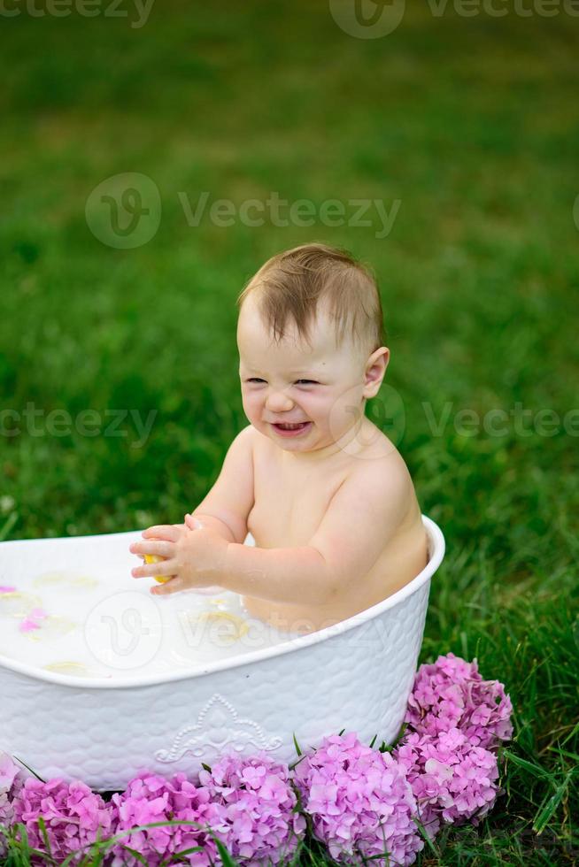 klein meisje baadt in een melkbad in het park. het meisje heeft plezier in de zomer. foto
