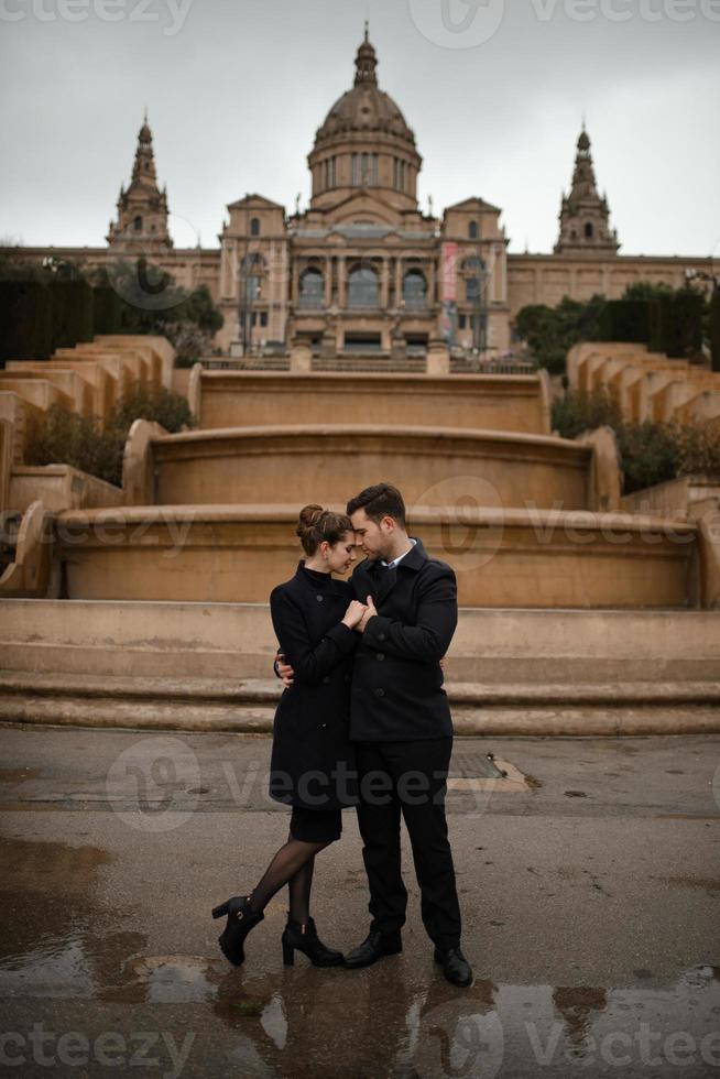 jonge mooie liefdevolle Spaanse paar loopt onder een paraplu tijdens de regen. foto