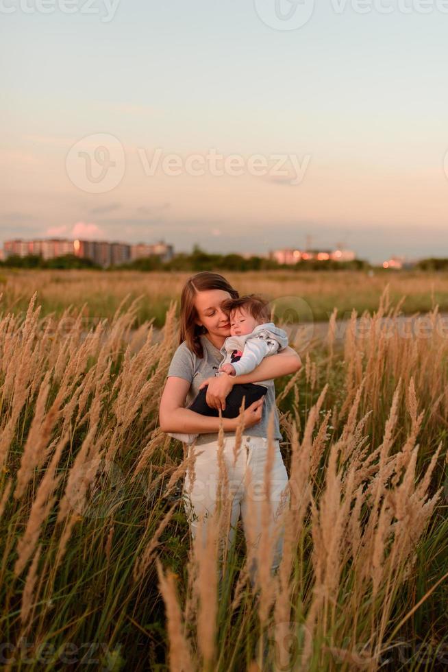 een moeder loopt in het veld met haar dochtertje in haar armen. foto