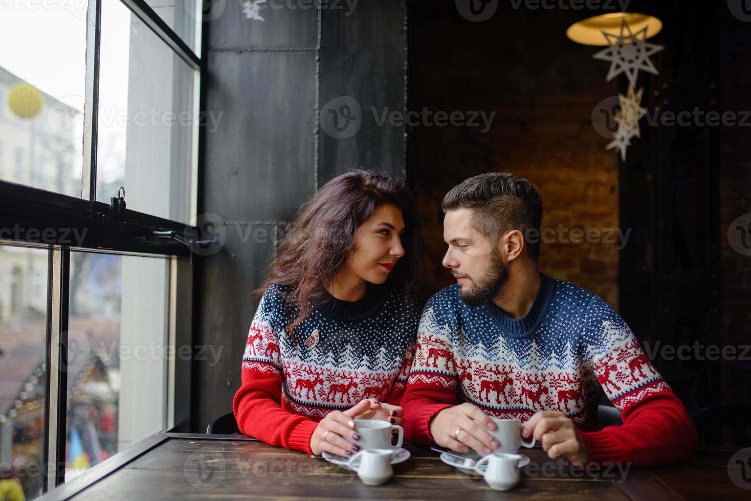 gelukkig en romantisch stel in warme truien drinkt koffie uit wegwerpbekers in de cafetaria. vakantie, kerst, winter, liefde, warme dranken, mensenconcept foto