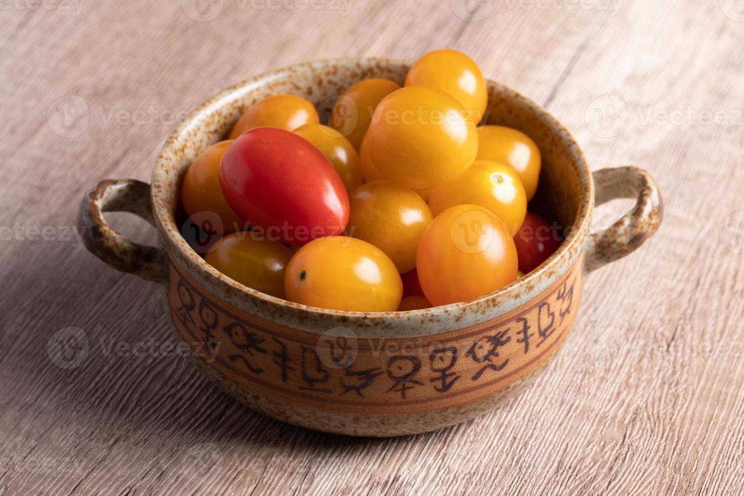 kleine gele tomaten in een kopje op houten achtergrond foto