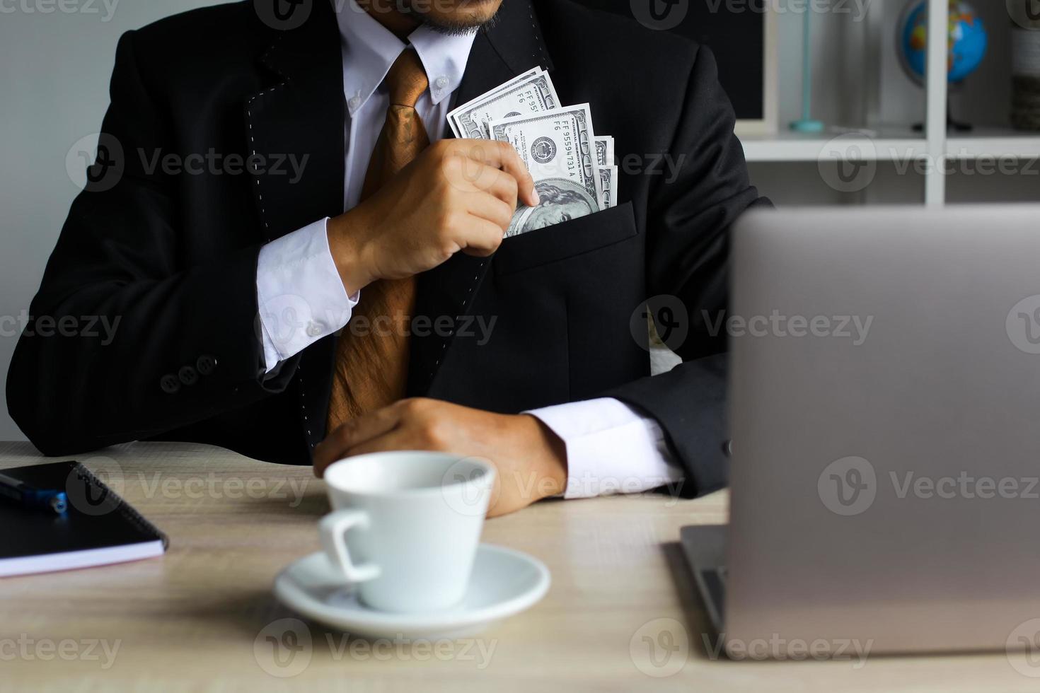 zakenman die dollarbiljetten op zijn zak op kantoor zet foto