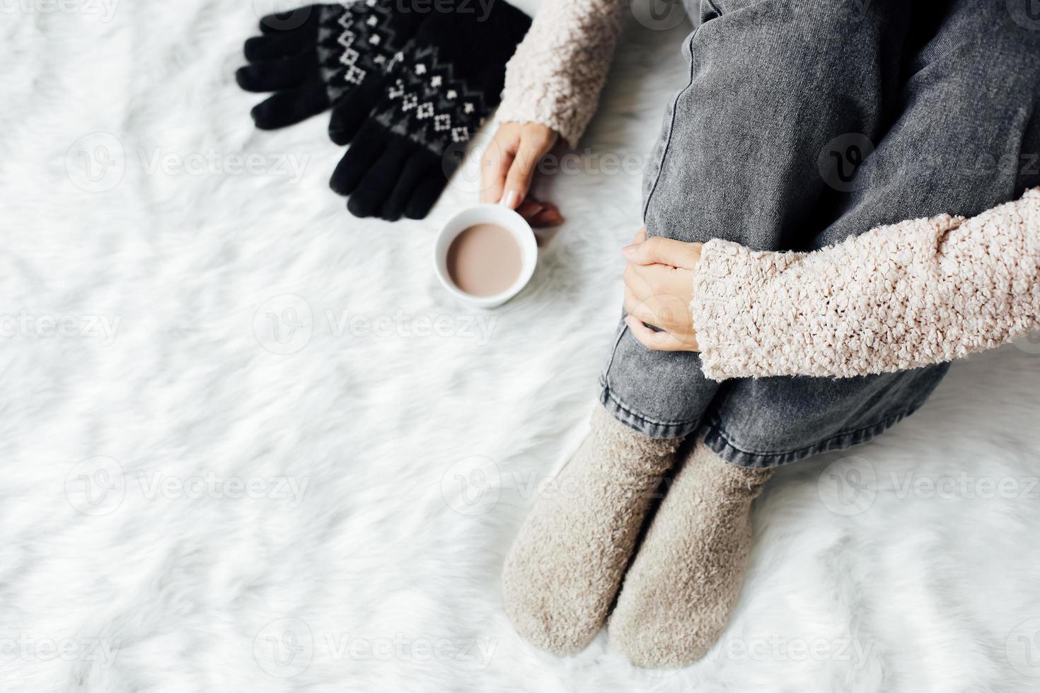 bovenaanzicht van een vrouw in winterkleren en sokken met een warme chocolademelk foto