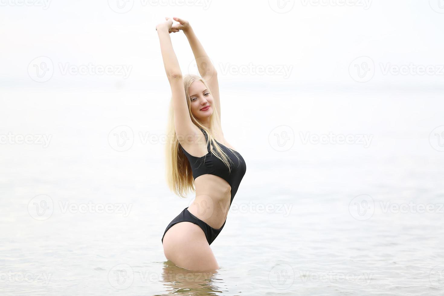 jonge vrouw genieten en ontspannen bij het zwembad. slank jong meisje model in witte bikini bij het zwembad. foto