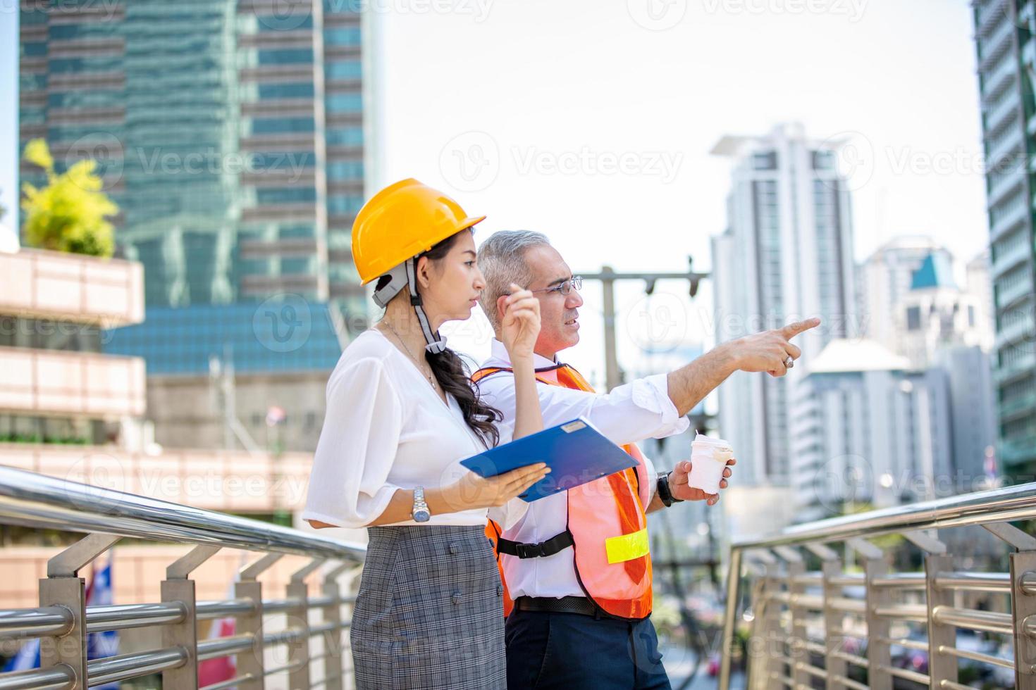 de ingenieur en zakenvrouw die op het klembord controleren bij de bouw van de bouwplaats. het concept van engineering, constructie, stadsleven en toekomst. foto