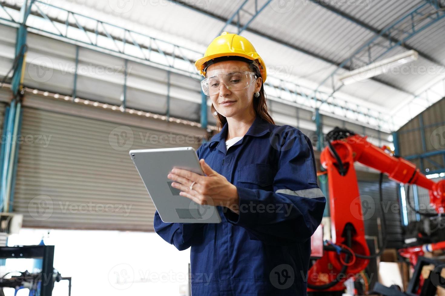 professionele jonge industriële fabrieksvrouw werknemer die met machineonderdeel werkt, industriële apparatuur en robotarmen controleert en test in grote elektrische elektronicadraad en fabriek foto