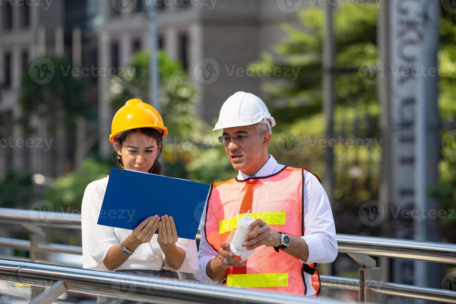 de ingenieur en zakenvrouw die op het klembord controleren bij de bouw van de bouwplaats. het concept van engineering, constructie, stadsleven en toekomst. foto