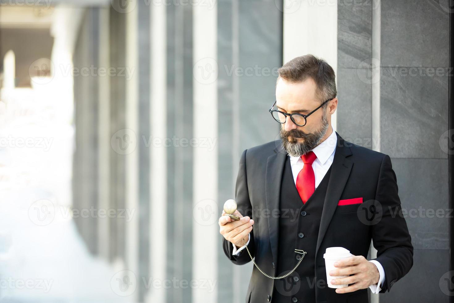 hipster zakenman in pak staande met koffiekopje in de buurt van kantoor buiten foto