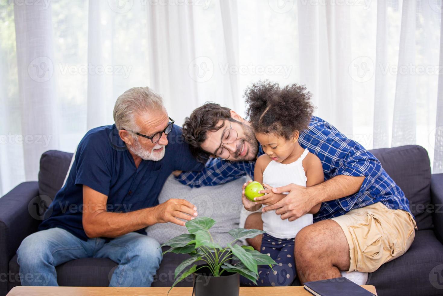 diverse vriendelijke familie zit op de comfortabele bank in een gezellige woonkamer, een multiraciale ouders en hun kinderen genieten van tijd samen thuis foto