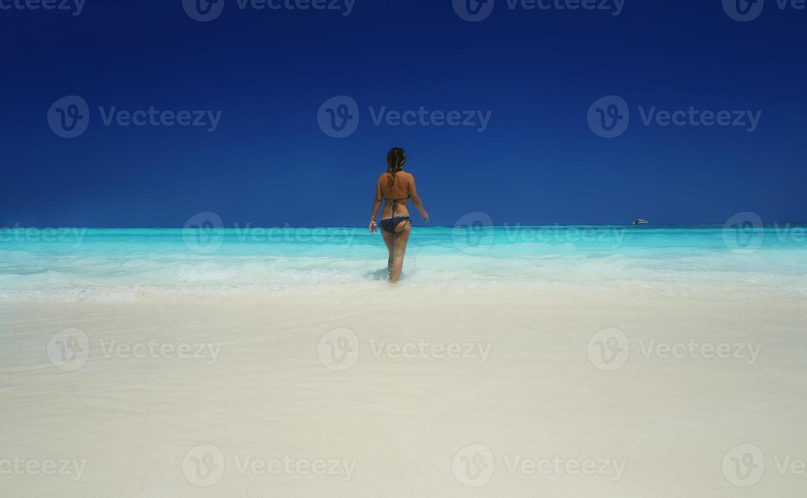 mooie blonde vrouw op zwarte bikini geniet van de zomer op het strand. foto