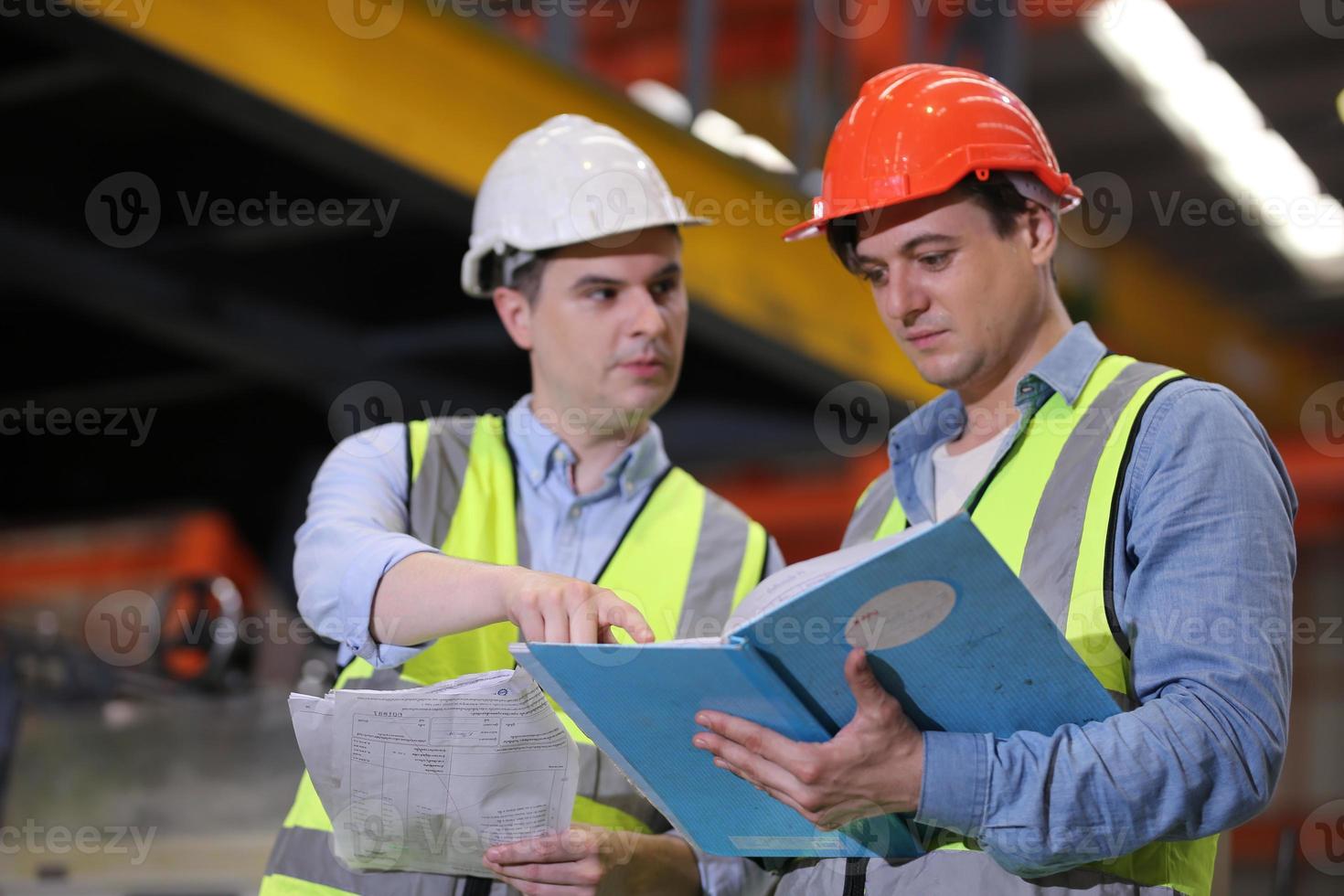 mannen industrieel ingenieur die een veiligheidshelm draagt terwijl hij in een zware industriële fabriek staat. het onderhoud van het werken aan industriële machines en het controleren van de installatie van het beveiligingssysteem in de fabriek. foto