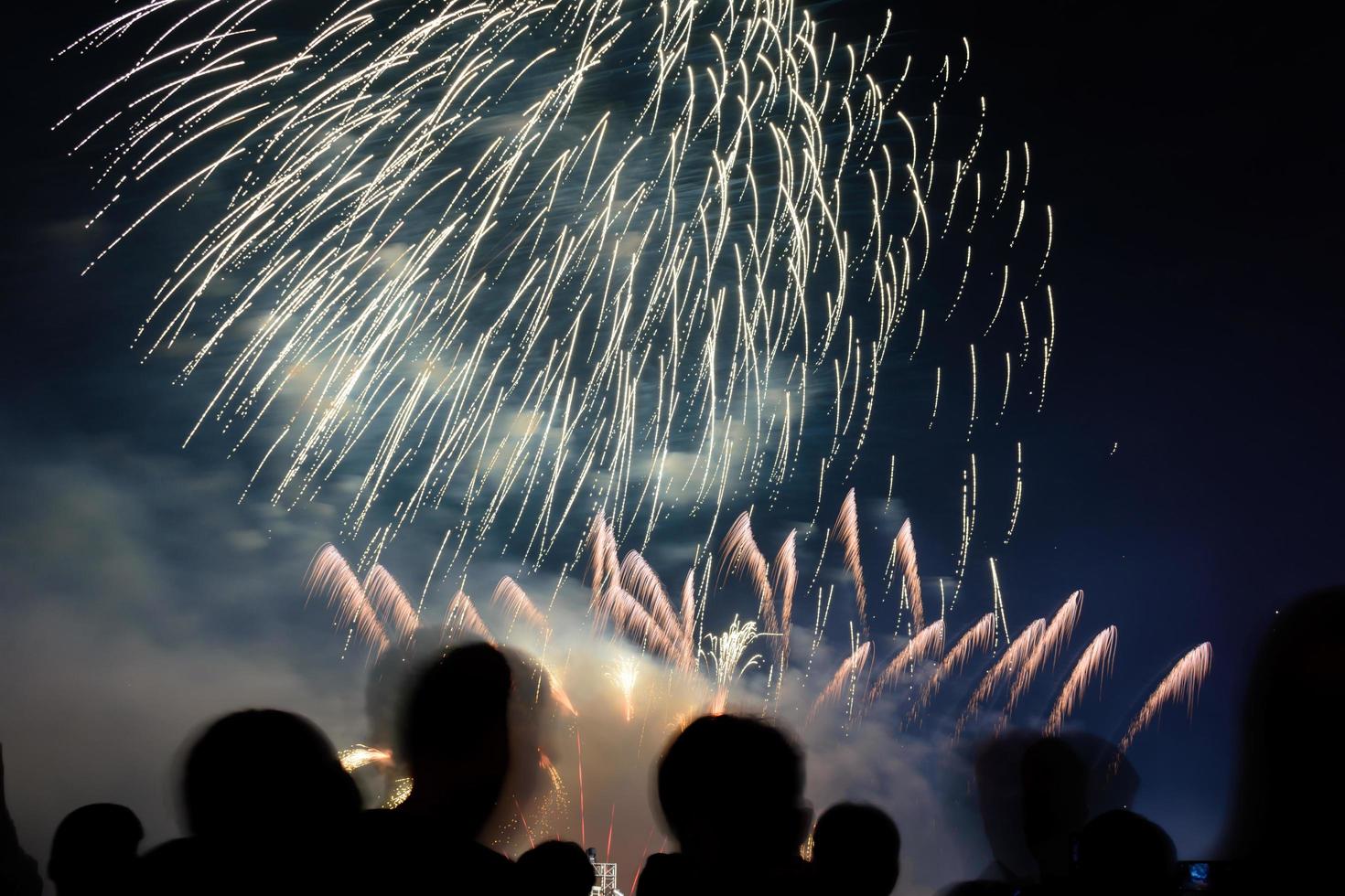 menigte kijken naar vuurwerk en vieren de stad gesticht. prachtig kleurrijk vuurwerk in de stad om te vieren op een donkere nachtachtergrond. foto