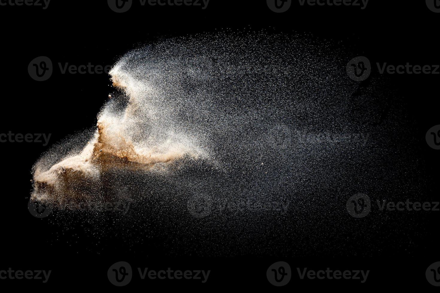 zand vliegende explosie geïsoleerd op zwarte achtergrond. bevriezen beweging van zandige stof splash. foto