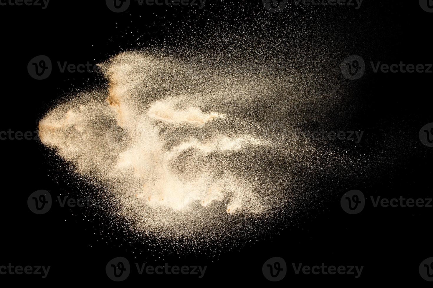 abstracte zandwolk. gouden gekleurde zandplons tegen donkere achtergrond. gele zandvlieggolf in de lucht. zand exploderen op zwarte achtergrond, bevriezen stop motion concept gooien. foto