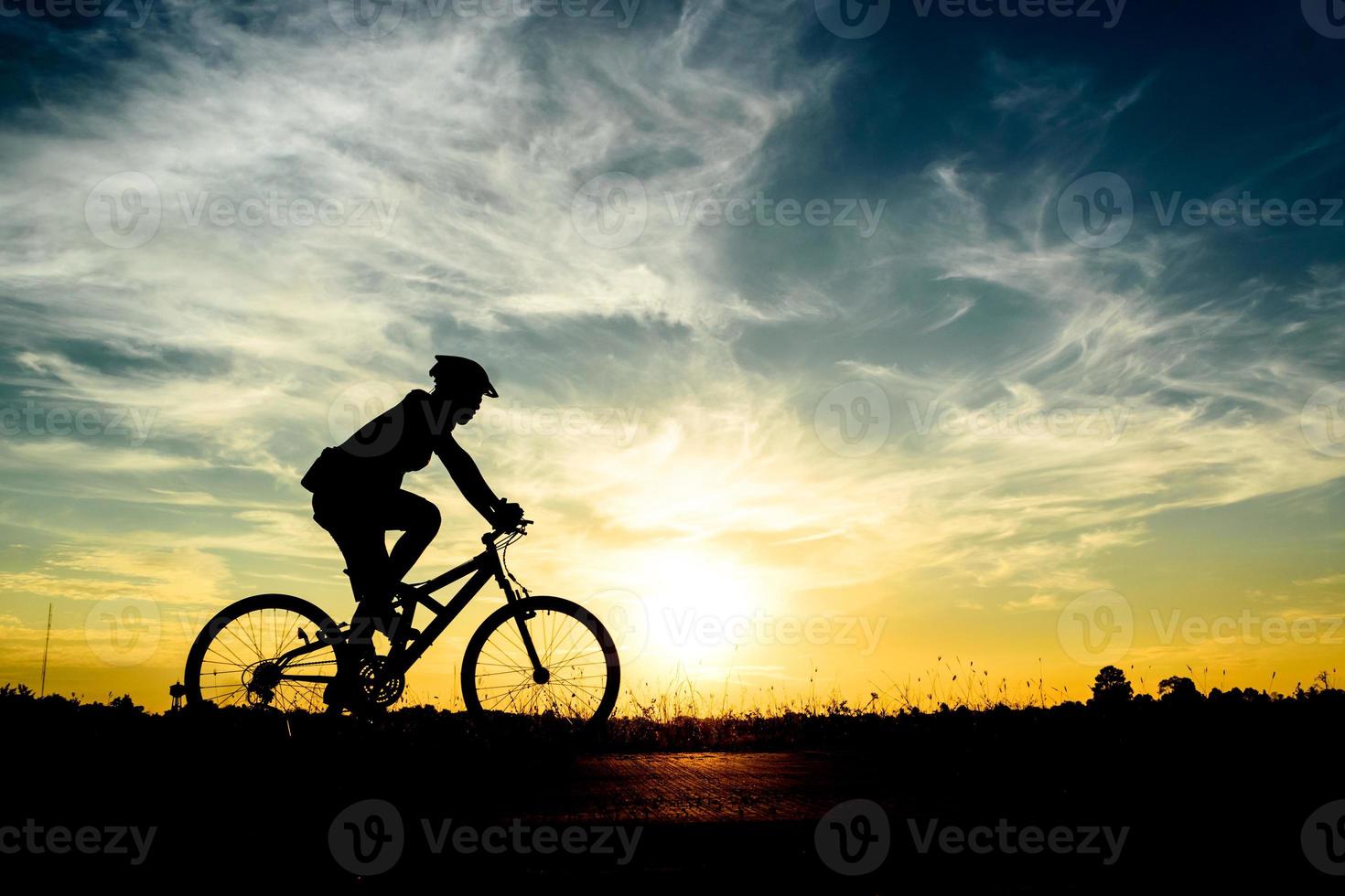 silhouet van fietser rijden op de fiets bij zonsondergang. foto