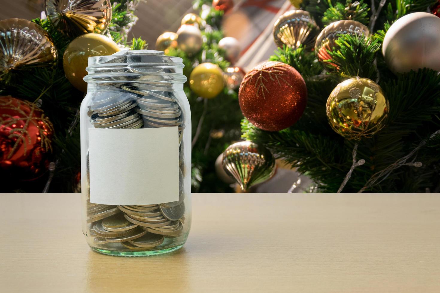 geld in de glazen fles met versierde kerstboom achtergrondvervaging foto