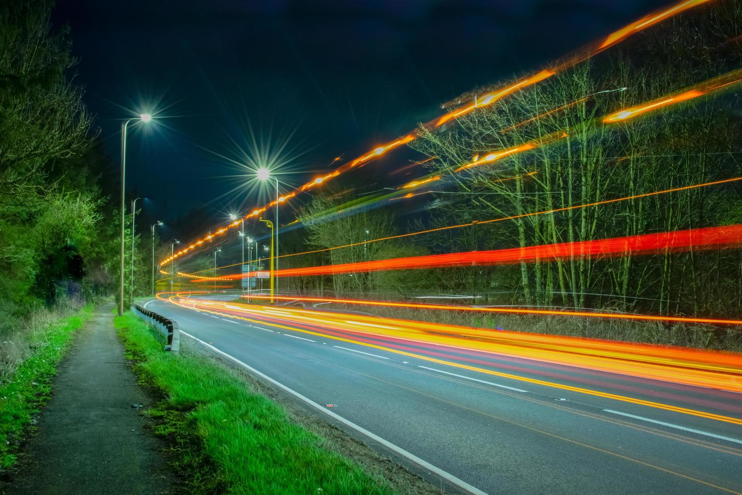 lichtsporen op stedelijke weg gecreëerd door lichten van vrachtwagens en auto's. foto