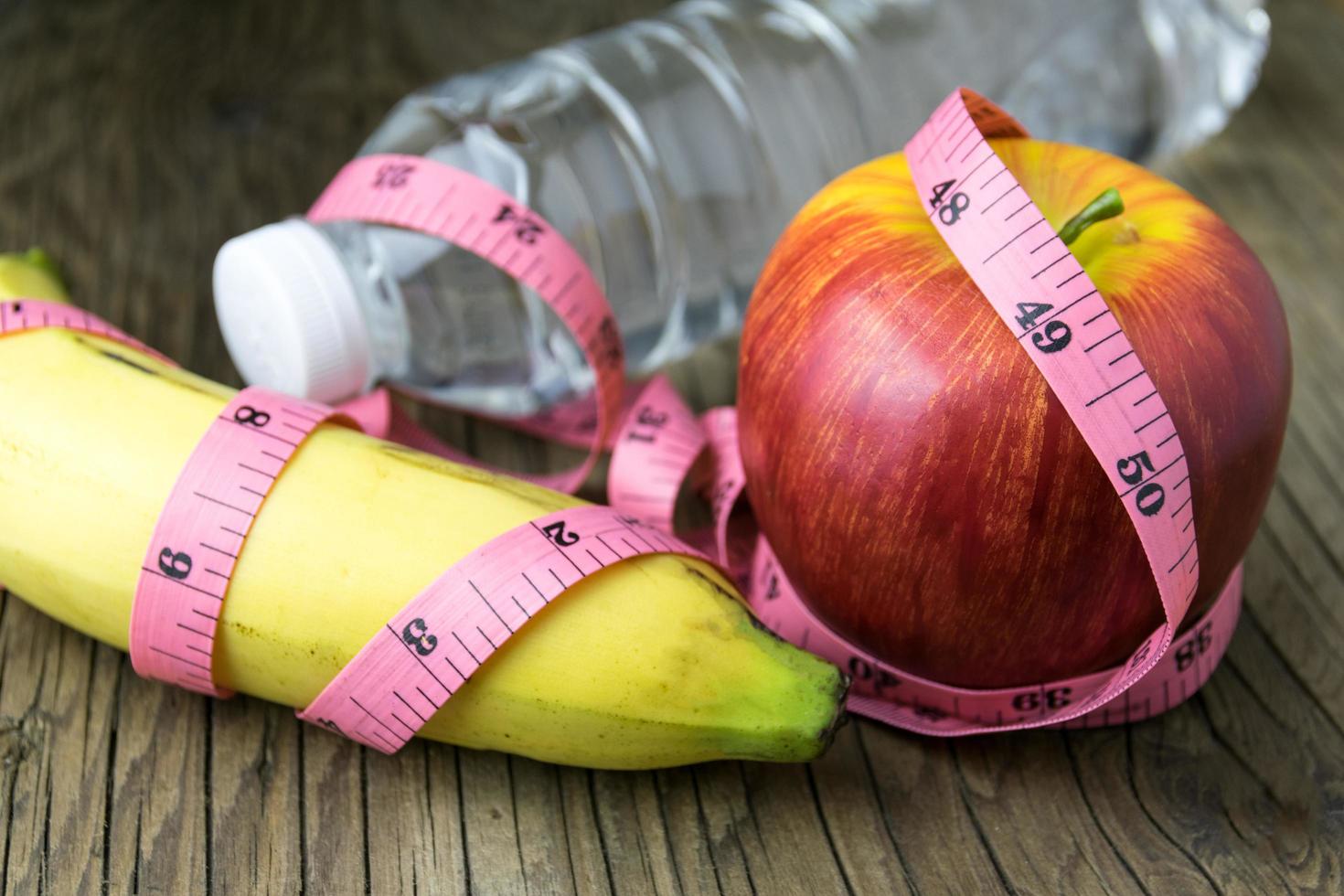 gezond eten concept, meetlint, fruit en waterfles op een houten ondergrond foto