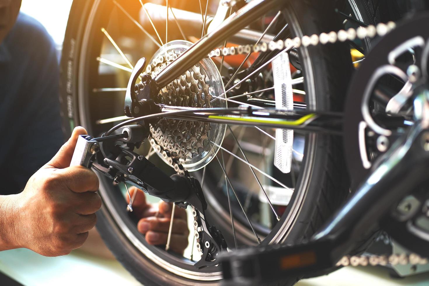 fietsenmaker repareert vouwfiets in werkplaats. achterderailleur afstellen, onderhouds- en reparatieconcept foto