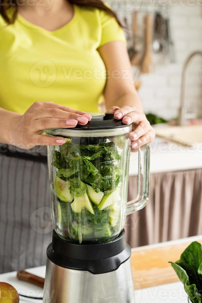 jonge vrouw die groene spinaziesmoothie maakt thuis keuken foto