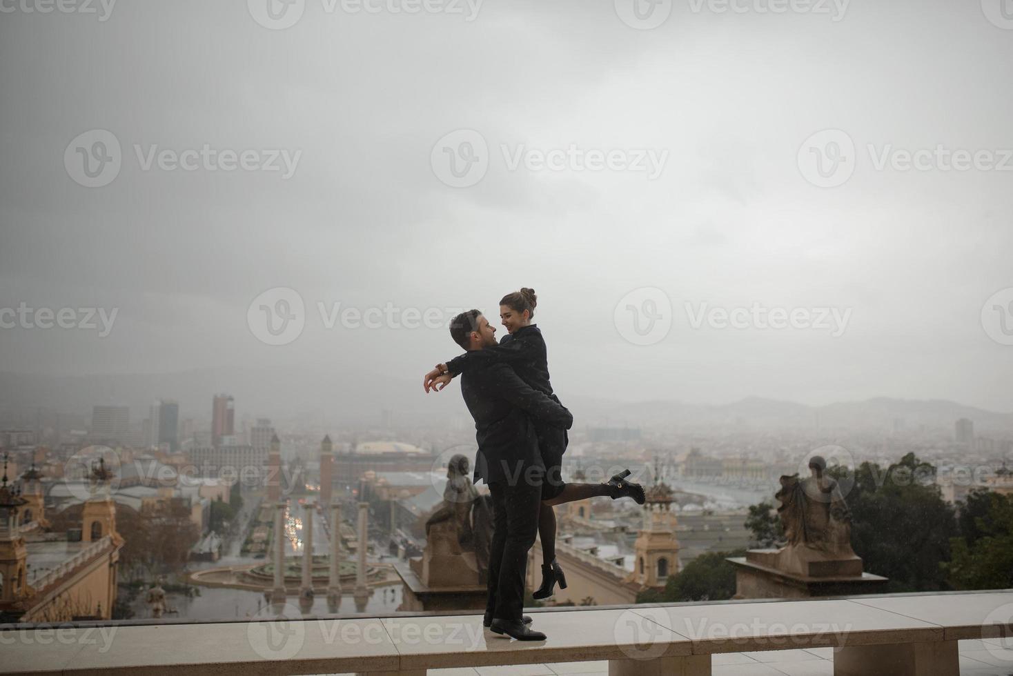 jonge mooie liefdevolle Spaanse paar loopt onder een paraplu tijdens de regen. foto