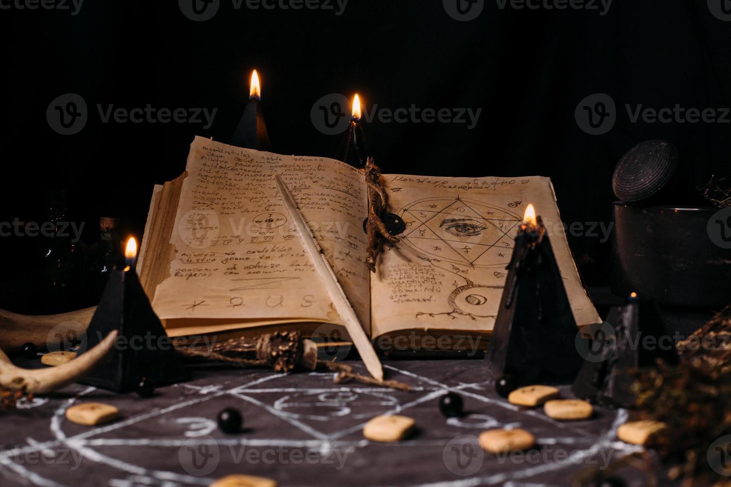 open oud boek met magische spreuken, runen, zwarte kaarsen op heksentafel. occult, esoterisch, waarzeggerij en wicca concept. foto