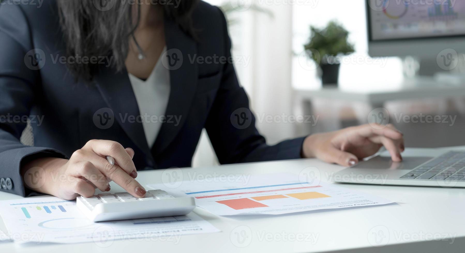 vrouw accountant gebruik rekenmachine en computer op bureau in kantoor. werken voor veilig thuis. financieel en boekhoudconcept foto
