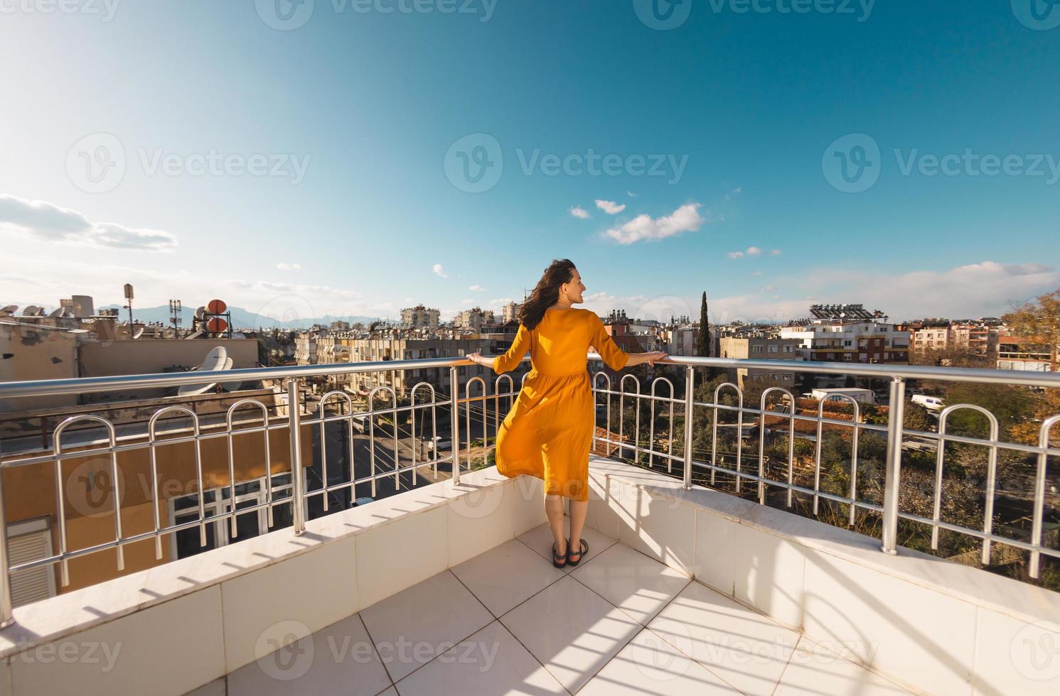 een aantrekkelijk meisje kijkt naar de stad en de wind blaast haar jurk op foto