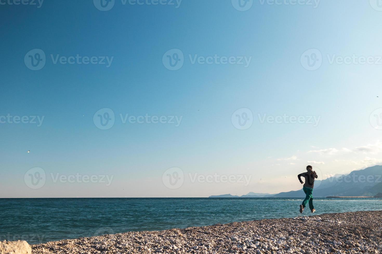 rennend op het zand, een vrouw rent langs het strand foto