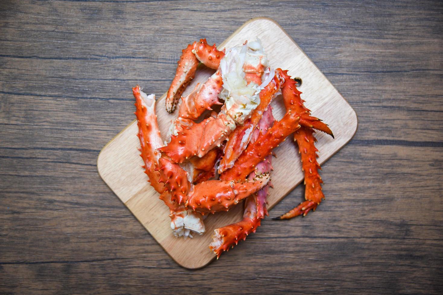 alaska koningskrab benen gekookte zeevruchten op houten snijplank achtergrond - rode krab hokkaido foto