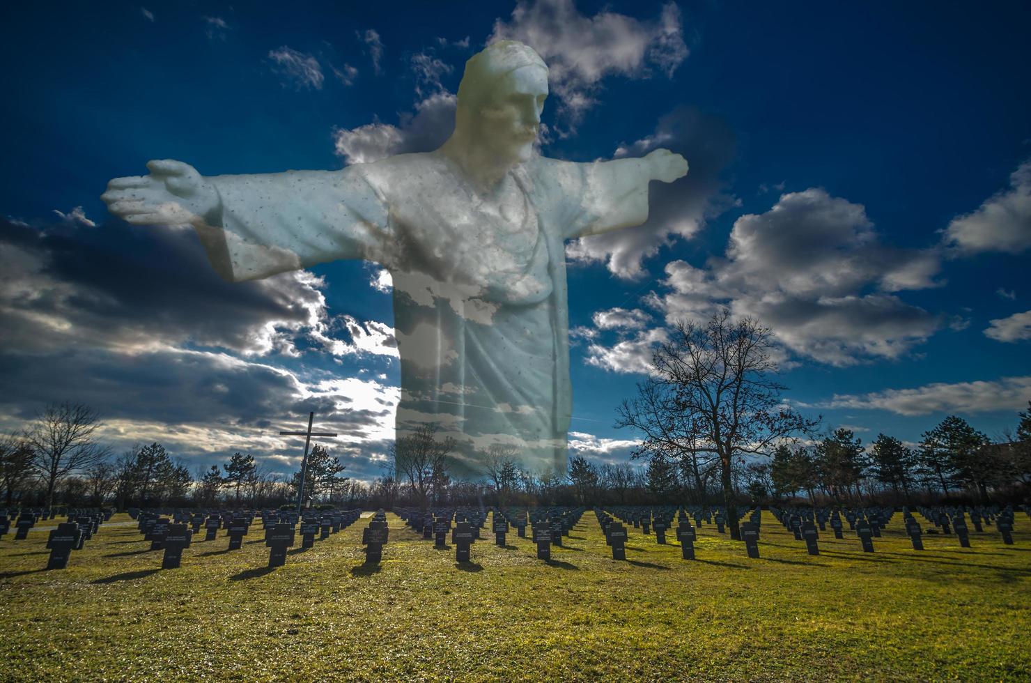 biddend Jezusbeeld voor vrijheid boven een militaire begraafplaats uit de wereldoorlog foto