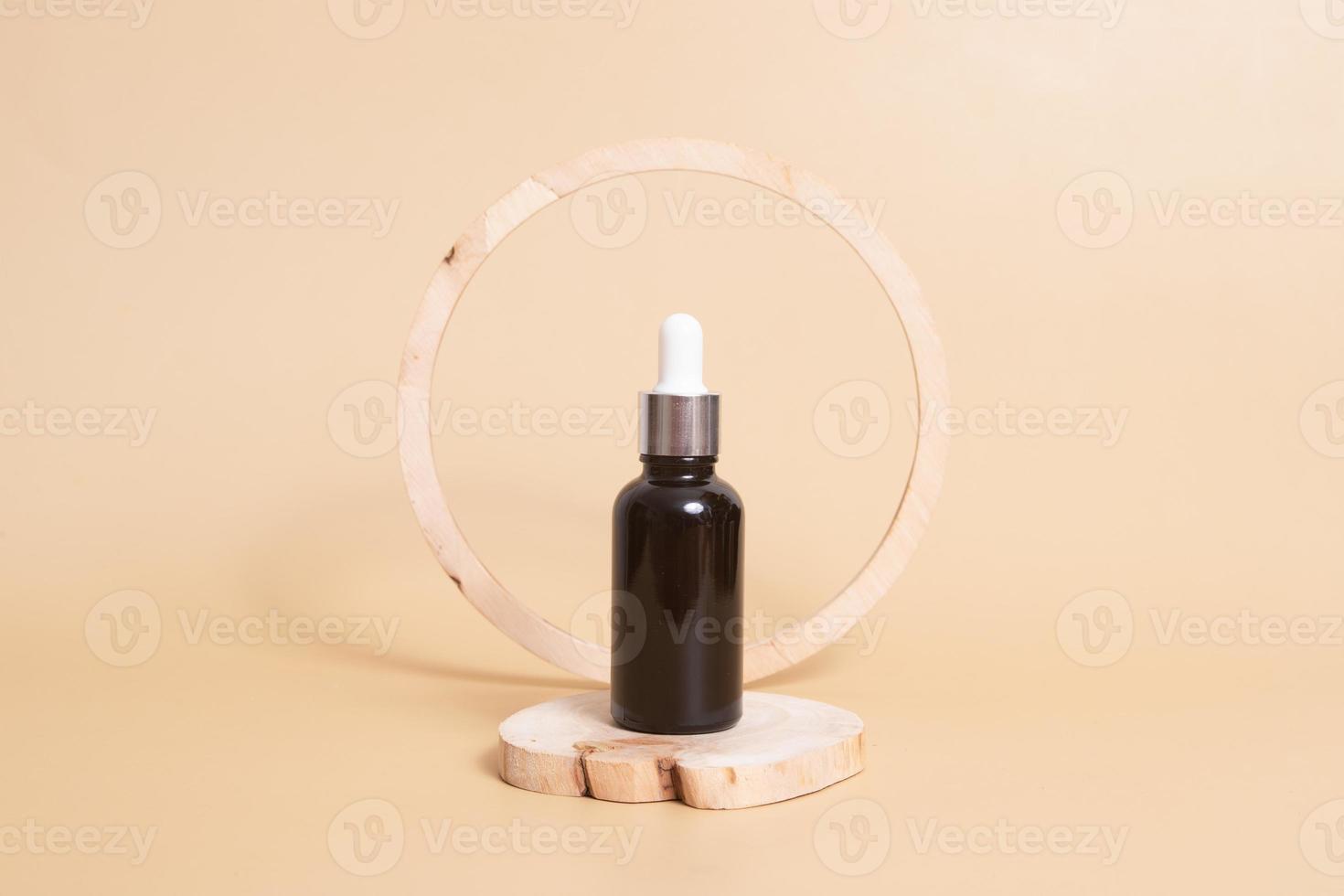 houten podium of voetstuk met een druppelflesje cosmetische olie of serum. neutraal beige monochroom huidverzorgingsconcept foto