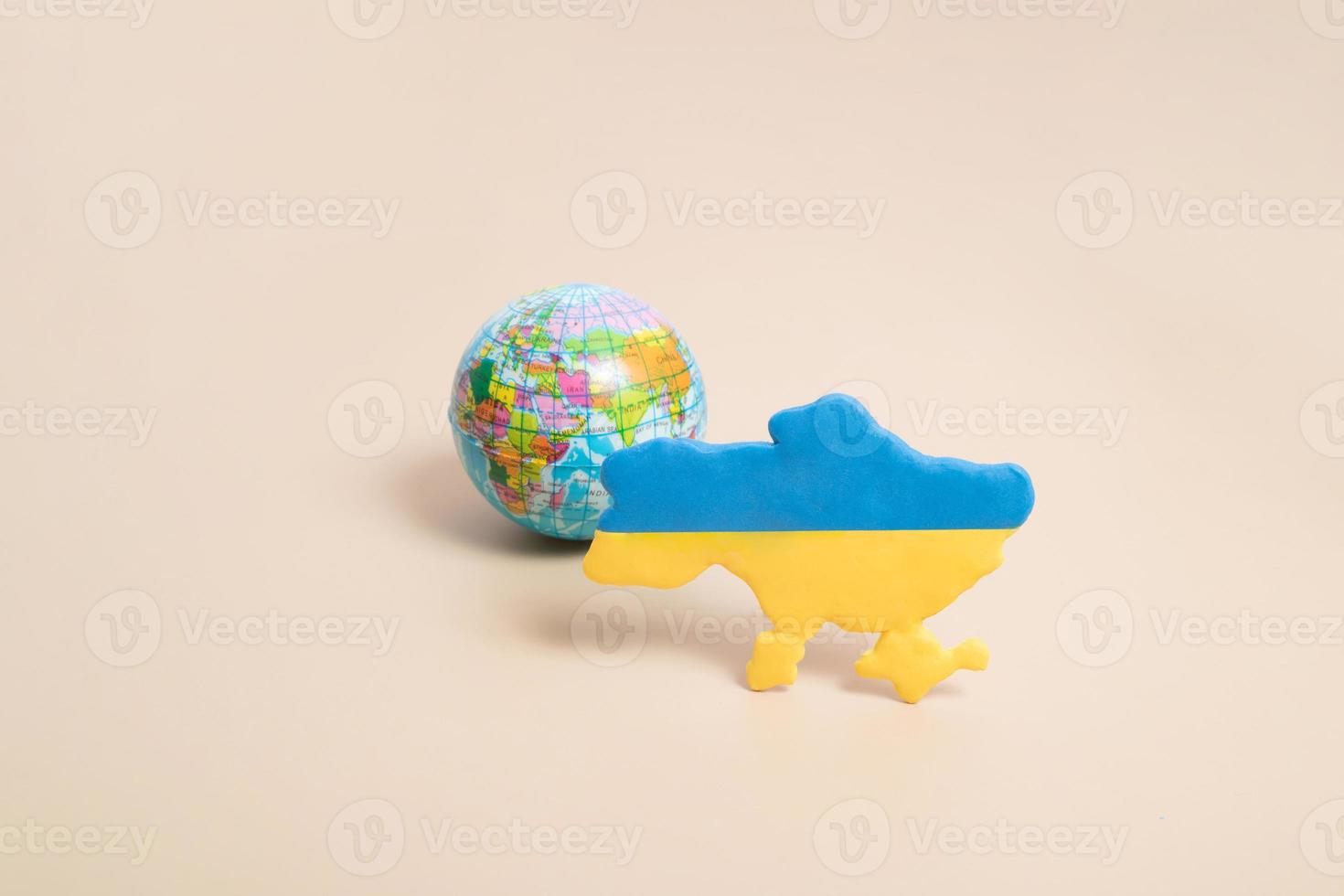 plasticine gele en blauwe kaart van oekraïne en de planeet aarde erachter. Oekraïne verdediger van het planeetconcept foto