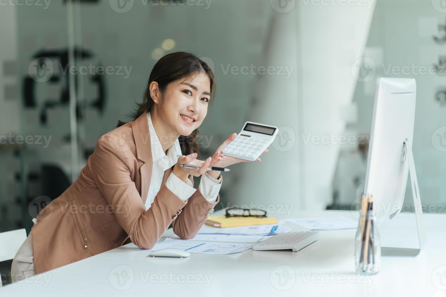 gelukkige aantrekkelijke aziatische zakenvrouw die werkt met een laptop en een financieel document op kantoor, succesvolle actie, bedrijfsconcept. foto