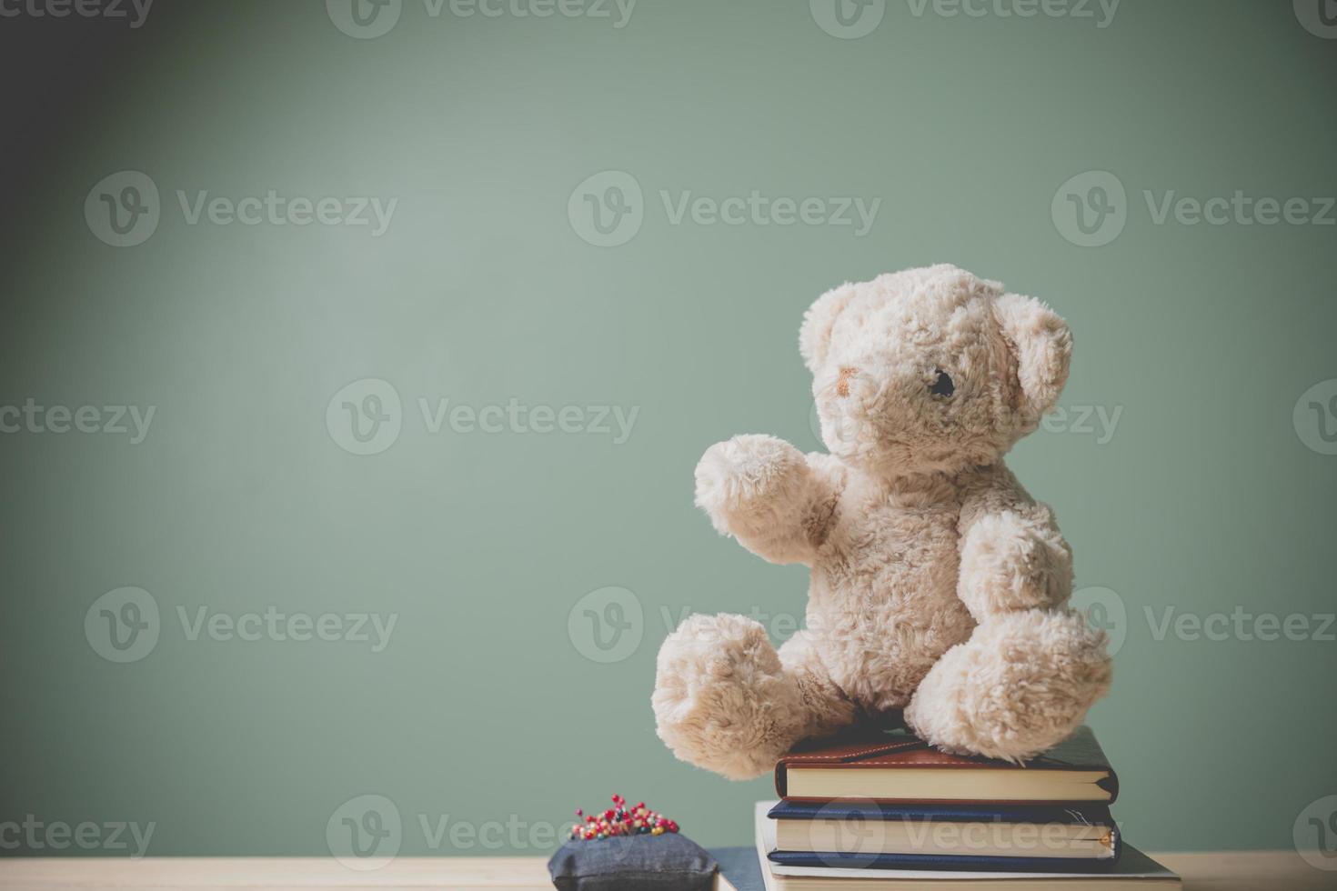 vintage beeldstijl. deze knuffelige pluizige pop is perfect voor kinderen. als een geschenk voor kinderen om te spelen. een enkele bruine teddybeer zittend op boeken oude houten tafel vullen triest, alleen met kopieerruimte. foto