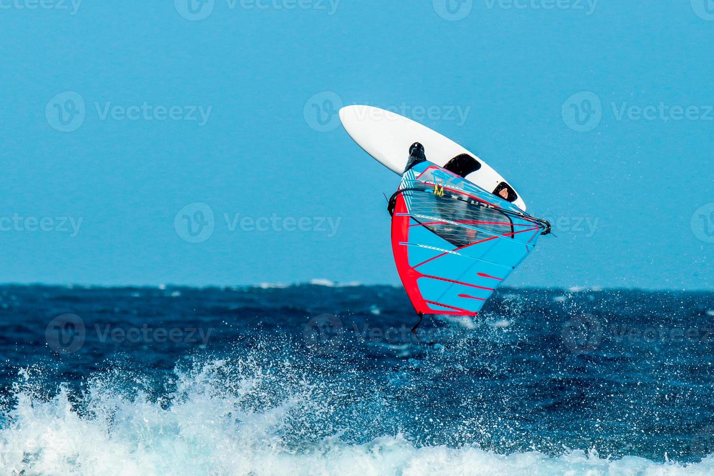 windsurfer die een acrobatische sprong maakt over de golven foto