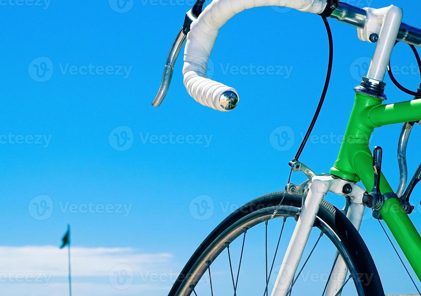 groene racefiets met het witte stuur op een blauwe hemelachtergrond foto