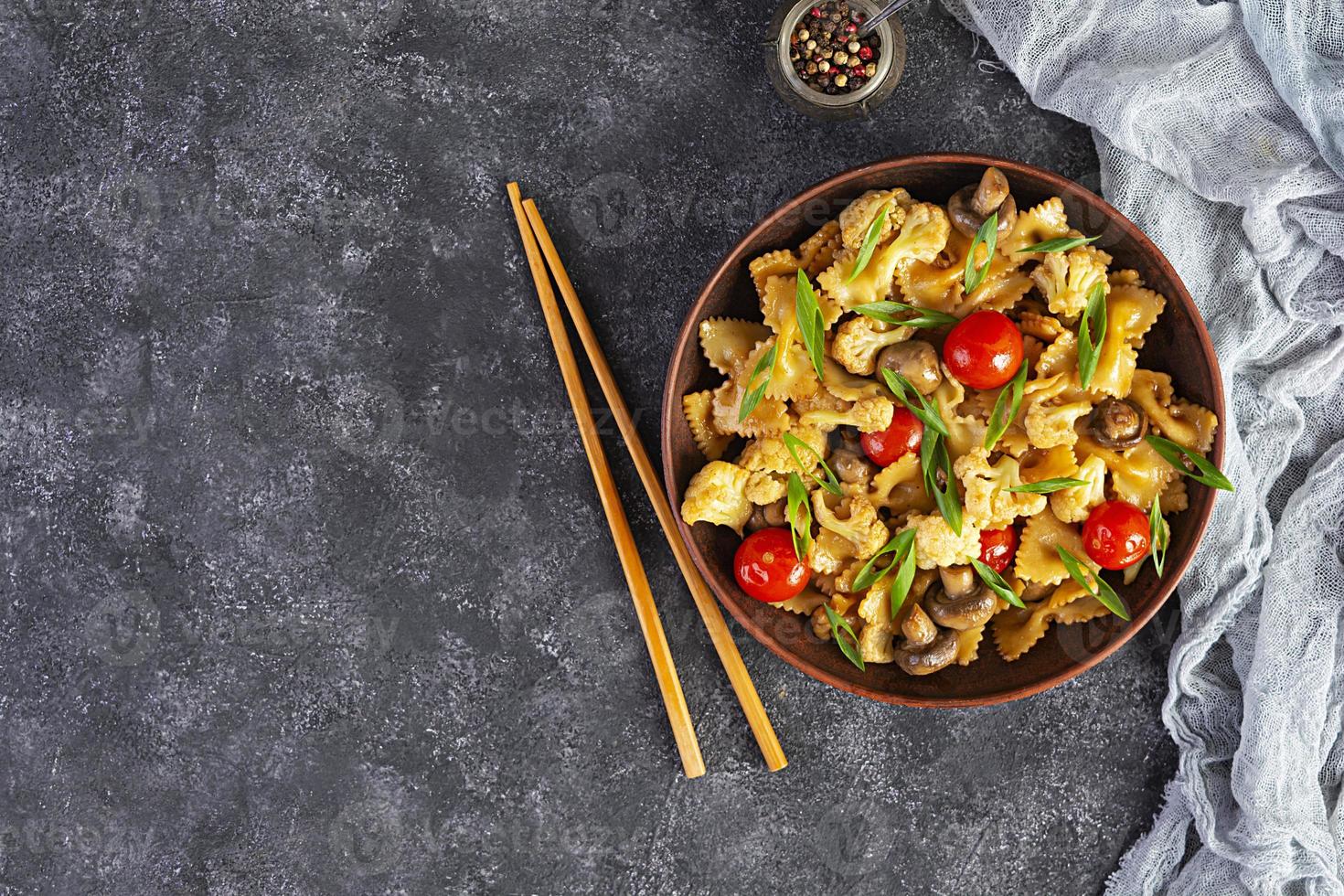 roerbak farfalle pasta met groenten, bloemkool en champignons. bovenaanzicht foto