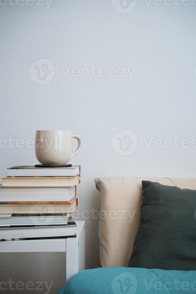 koffiekopje theemok op stapel boeken naast een bed foto