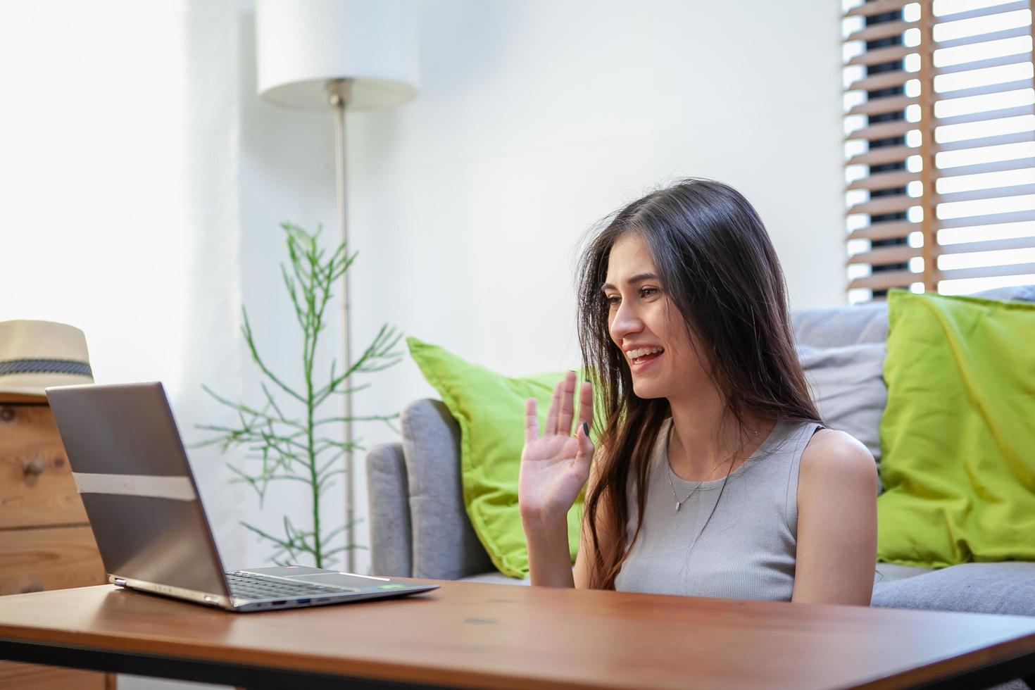 mooie jonge vrouw die op laptopcomputer werkt terwijl ze in de woonkamer zit foto