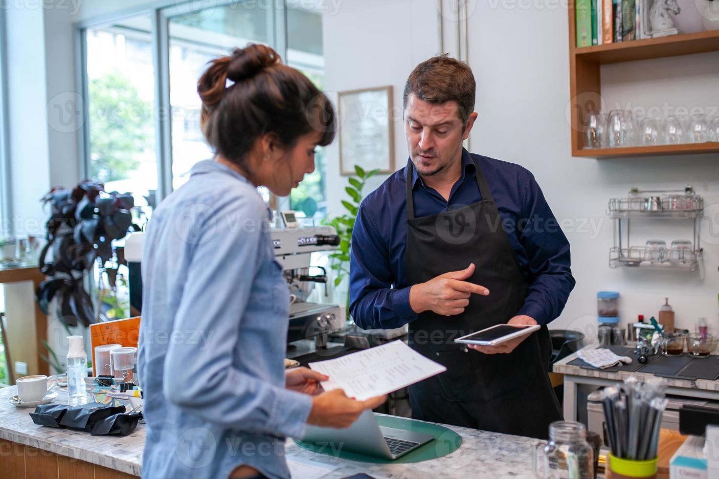 gelukkige barista neemt bestelling op met tablet van klant in coffeeshop. foto