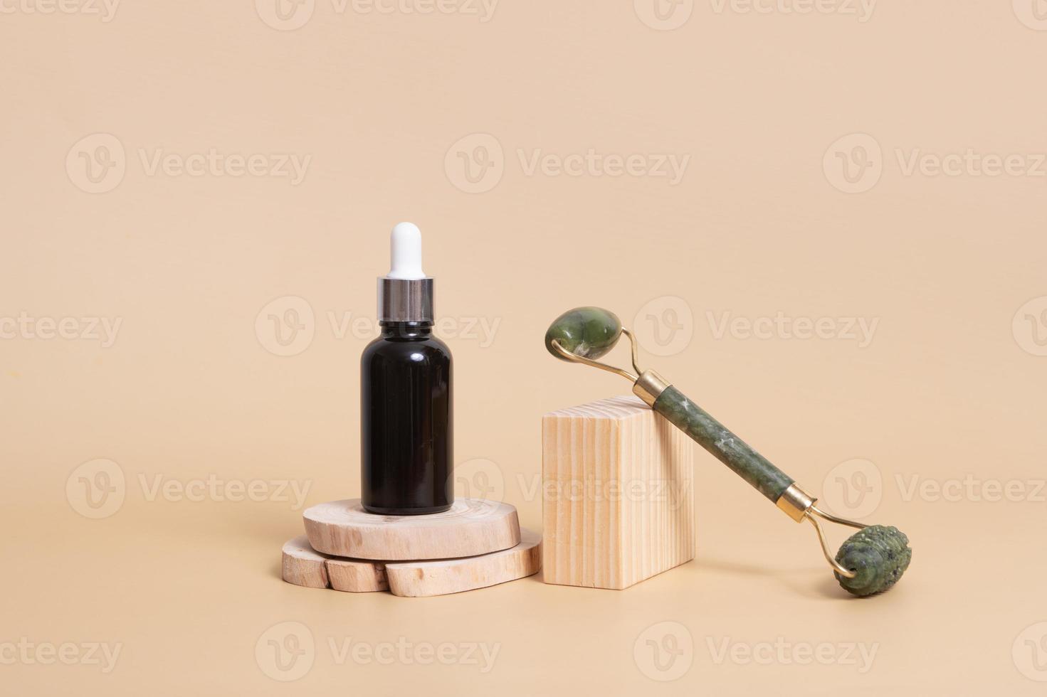 druppelflesje met cosmetische olie en gezichtsmassager op houten podia. gezichtsverzorgingsconcept in rustieke stijl foto